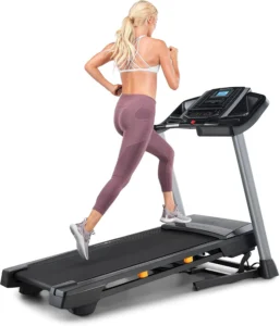Woman running on the NordicTrack T 6.5 S treadmill, rear three-quarter view showing grey side rails and LCD console