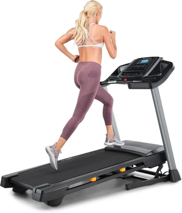 Woman running on the NordicTrack T 6.5 S treadmill, rear three-quarter view showing grey side rails and LCD console
