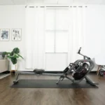 Sunny AquaStrive water rower on a treadmill mat in a home gym room
