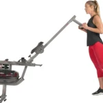 Man standing beside the upright folded Sunny AquaStrive water rower for storage