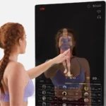 Close-up of a woman touching the Echelon Reflect's glass touchscreen mid-workout