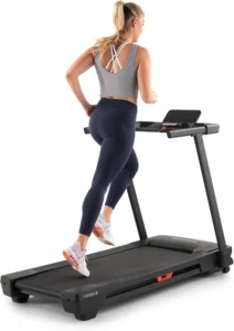 Woman running on the NordicTrack T Series T5 treadmill, rear angle with T Series 5 badge visible on the deck