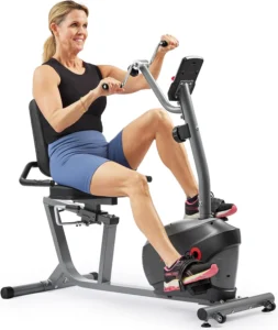 Woman using the hand cycle arms while pedaling the Sunny Health & Fitness Smart Magnetic Recumbent Bike, padded seat and console visible