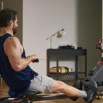 Man rowing the Sunny smart magnetic rower in a home gym, side angle