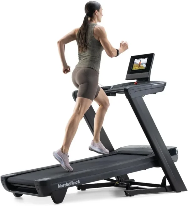 Woman running on the NordicTrack Commercial 1250 treadmill, rear three-quarter view with 10 inch touchscreen
