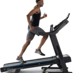 Man running on the Horizon 7.0 AT treadmill, side profile mid-stride
