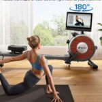 Woman doing a Pilates stretch beside the Merach Q1S rower with its screen rotated 180 degrees