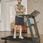 WELLFIT treadmill in a home setting, man standing beside the unit