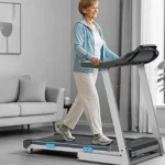 Senior woman walking on the WELLFIT Heavy Duty 15 percent auto incline foldable treadmill in a living room