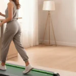 Woman using the Vitalwalk Apollo 11-Max walking pad at a standing desk