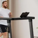 Renestar folding treadmill, frontal view with a larger-bodied user and tablet holder