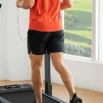 Rear view of a man running on the WELLFIT 400+ lb treadmill in front of a window