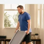 Man carrying the folded MERACH UltraWalk W60 walking pad by its handle for storage