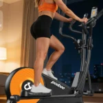 Woman using the pooboo E399 elliptical at night with a city skyline visible through the window