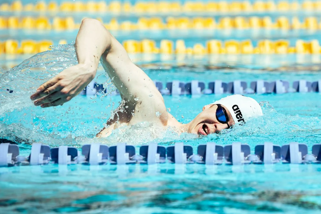 Swimmer doing freestyle stroke in a competition pool with lane dividers