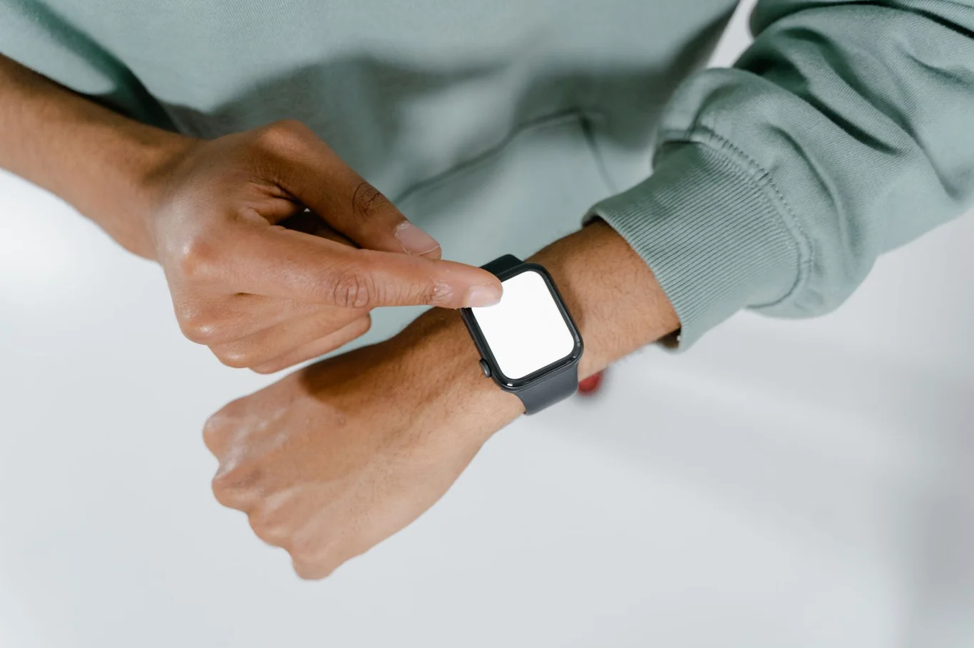 Person pressing Apple Watch touchscreen with index finger on wrist
