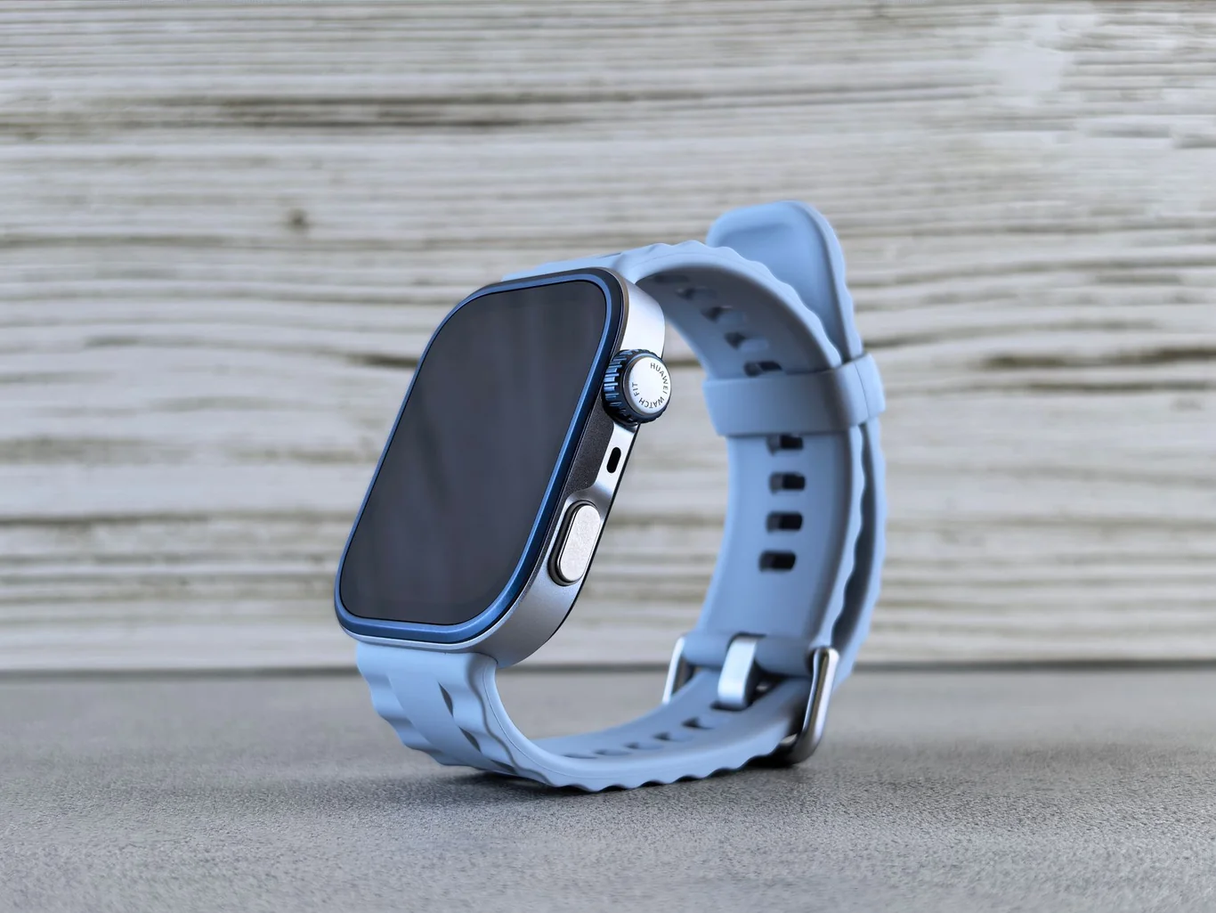 Apple Watch with a blue sport band resting on a gray surface