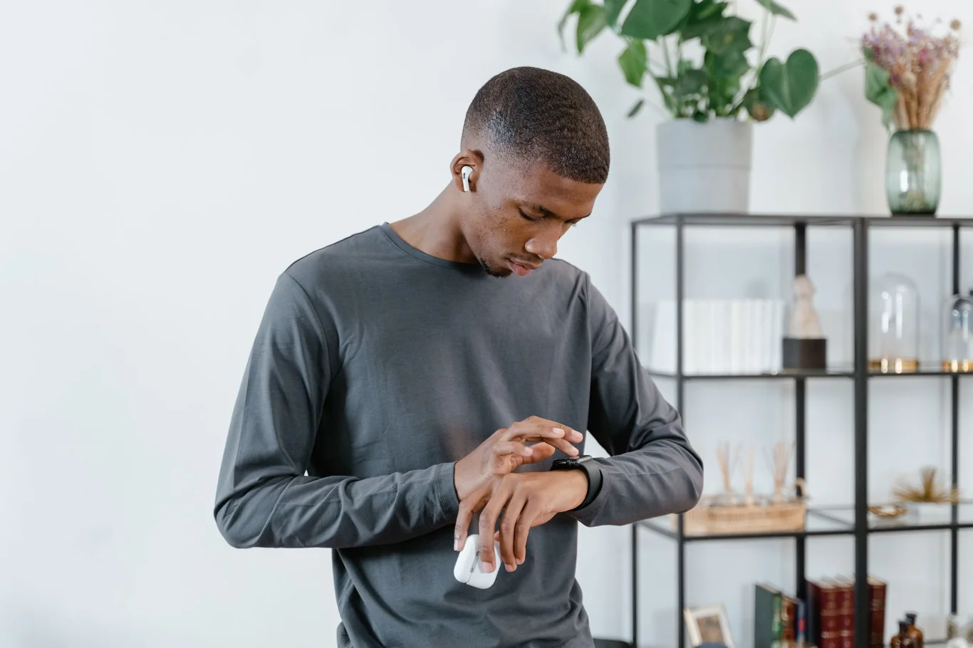Man checking a fitness tracker on his wrist while wearing wireless earbuds