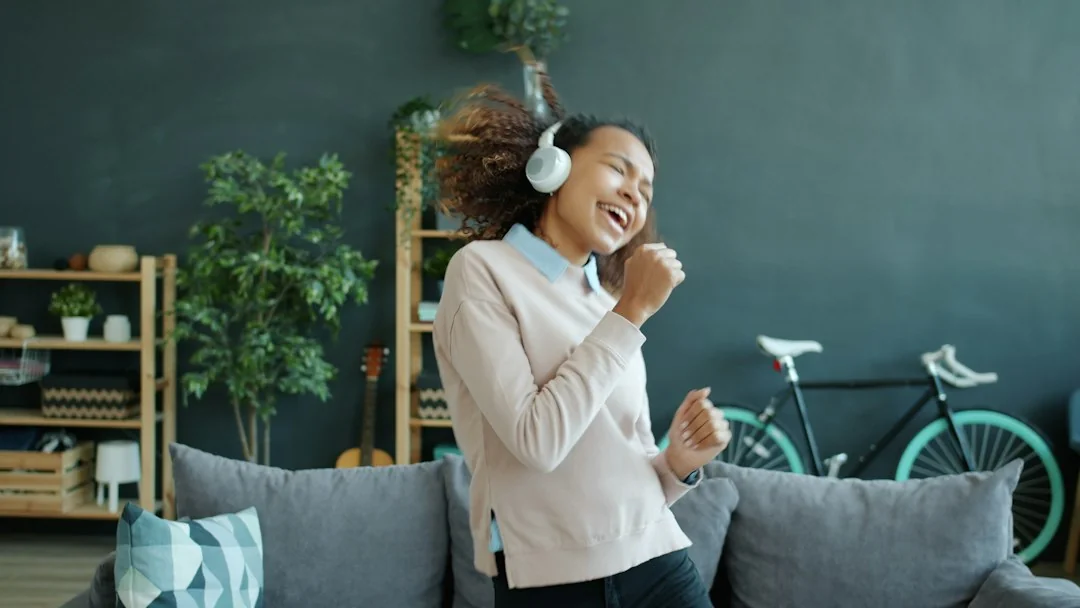 Woman with headphones dancing in a living room with a bicycle in the background