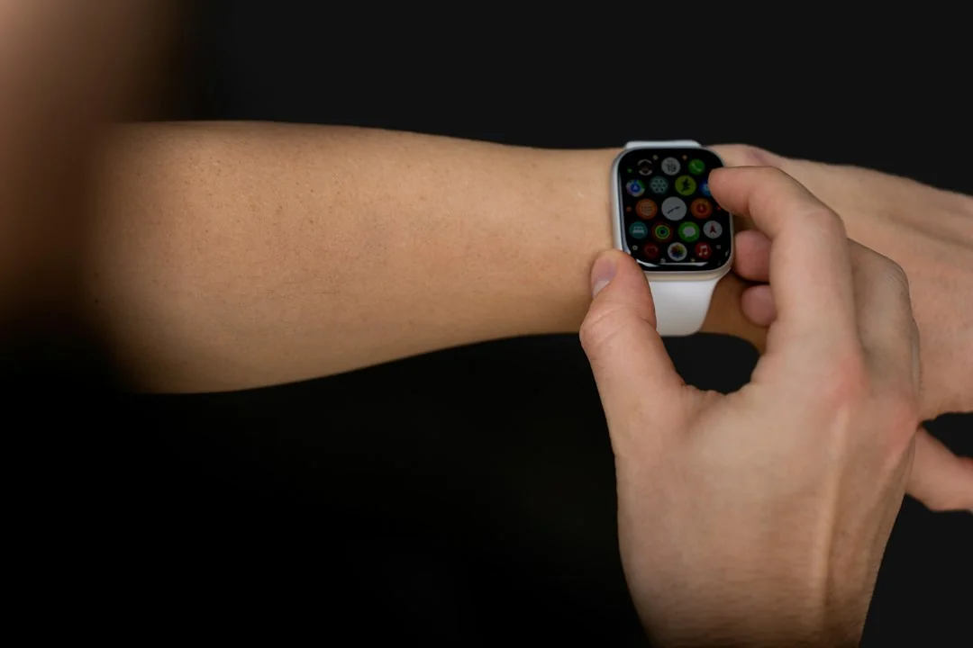 Hand tapping an Apple Watch with colorful app icons on a dark background