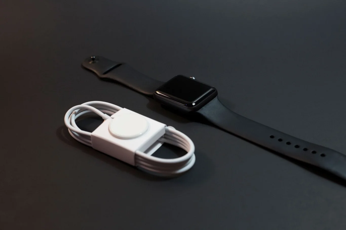 Apple Watch and magnetic charging cable on a dark surface