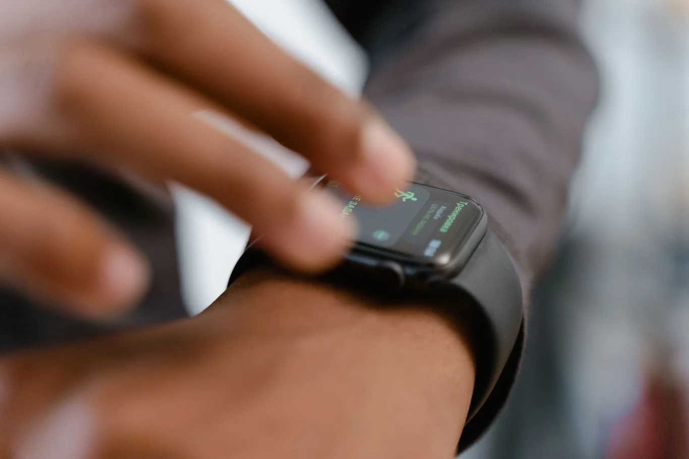 Person tapping a smartwatch screen displaying health metrics on their wrist