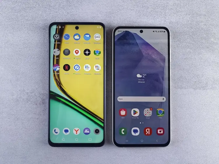 Two Android smartphones placed side by side on a gray surface showing home screens