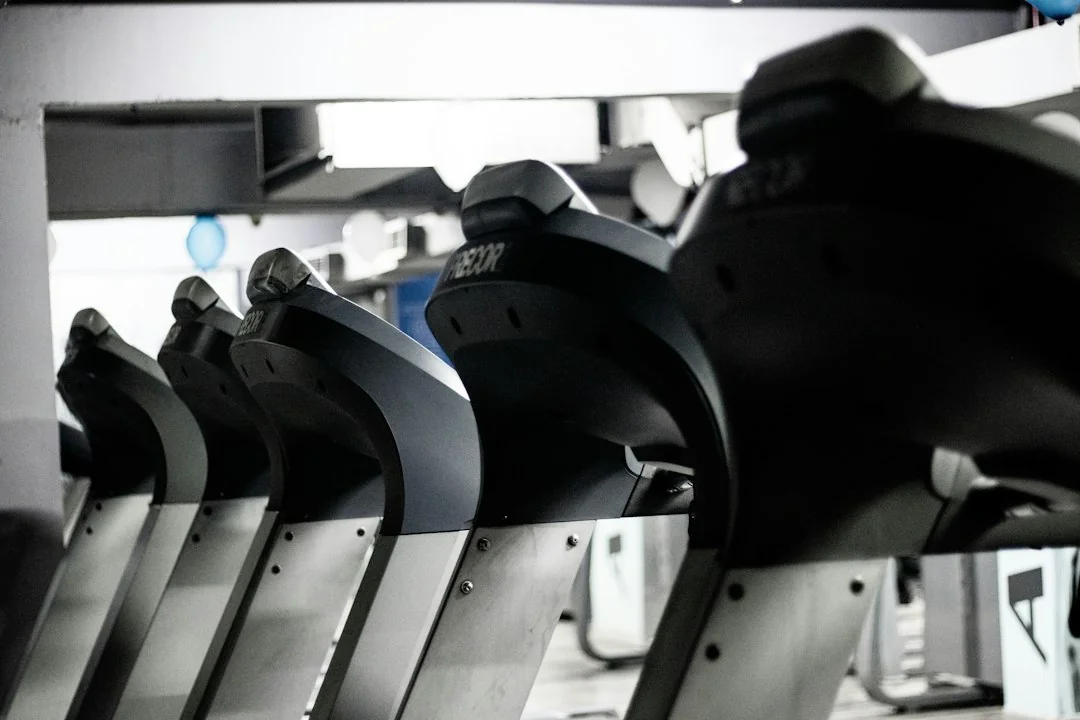 A row of stationary exercise bikes lined up in a gym ready for a cycling class