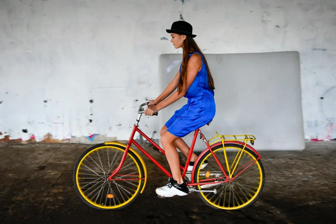 Woman in blue dress riding a red and yellow bicycle indoors