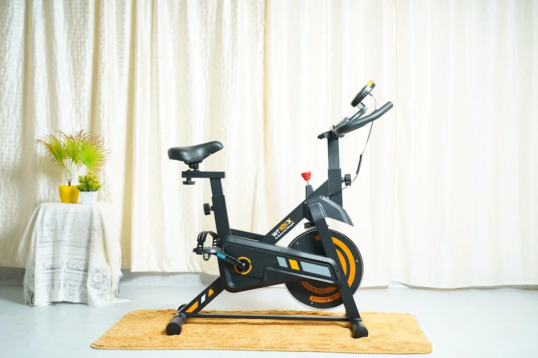 Black and orange spin bike on a rug in a bright home room with curtains