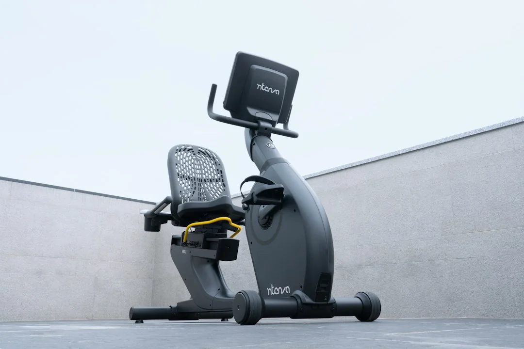 Modern recumbent exercise bike with mesh seat and touchscreen display on concrete background