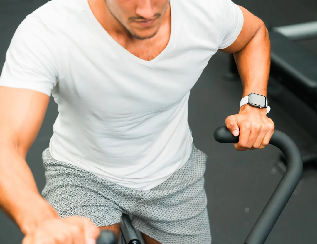 Man in a white shirt cycling hard on a stationary bike during an indoor workout