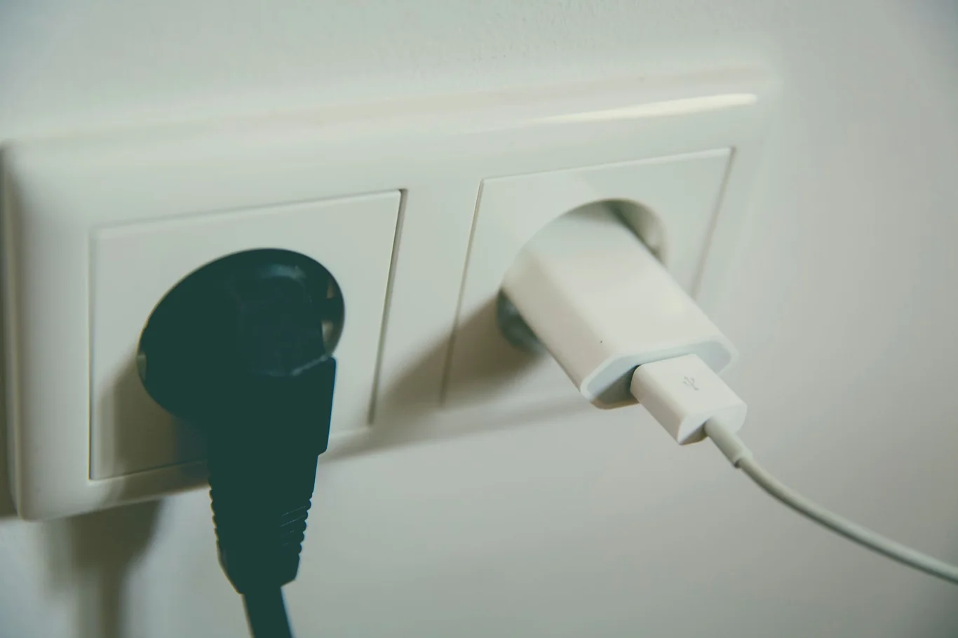 Two power plugs inserted into white wall outlets