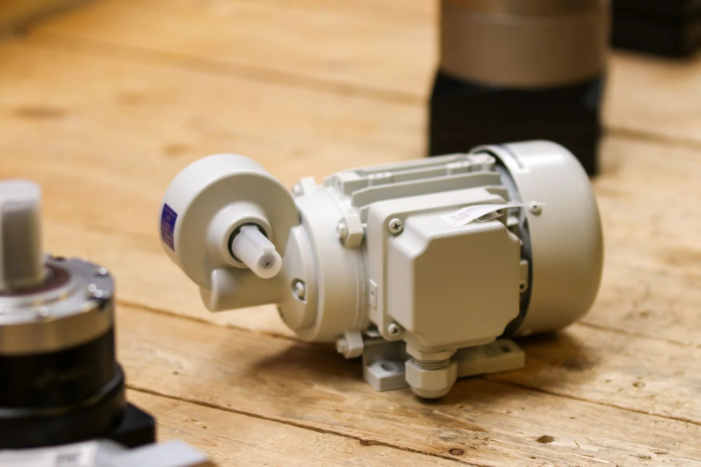 White electric motor replacement unit sitting on a wooden workshop floor