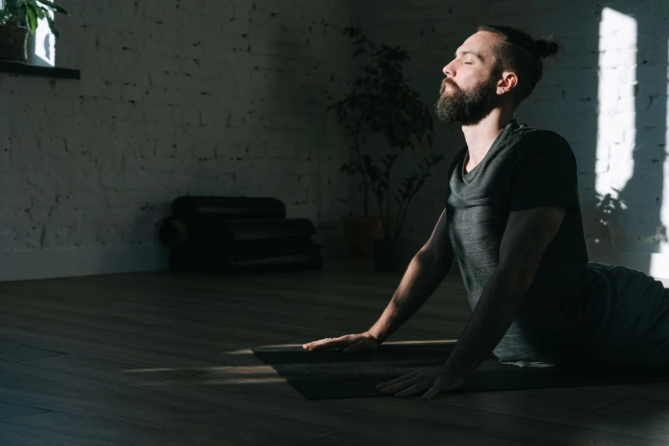 Man doing a cobra yoga stretch on the floor in a bright home studio