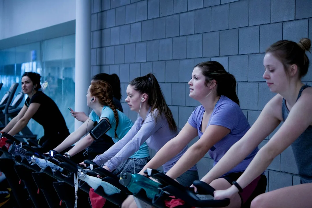 Group of women riding stationary bikes side by side during an indoor cycling class