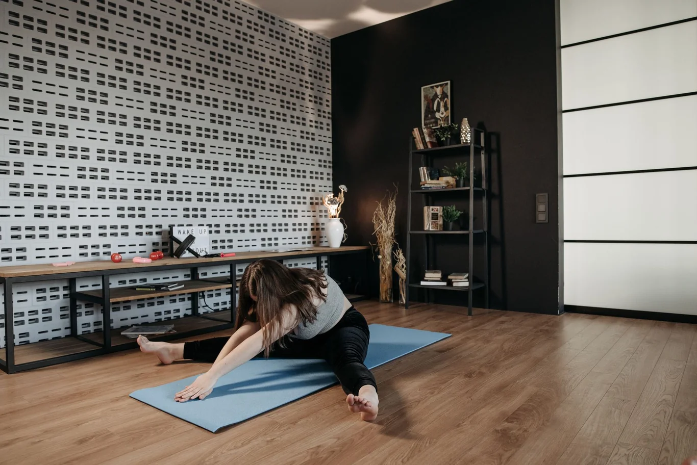 Woman doing a side stretch on a blue yoga mat on the floor at home