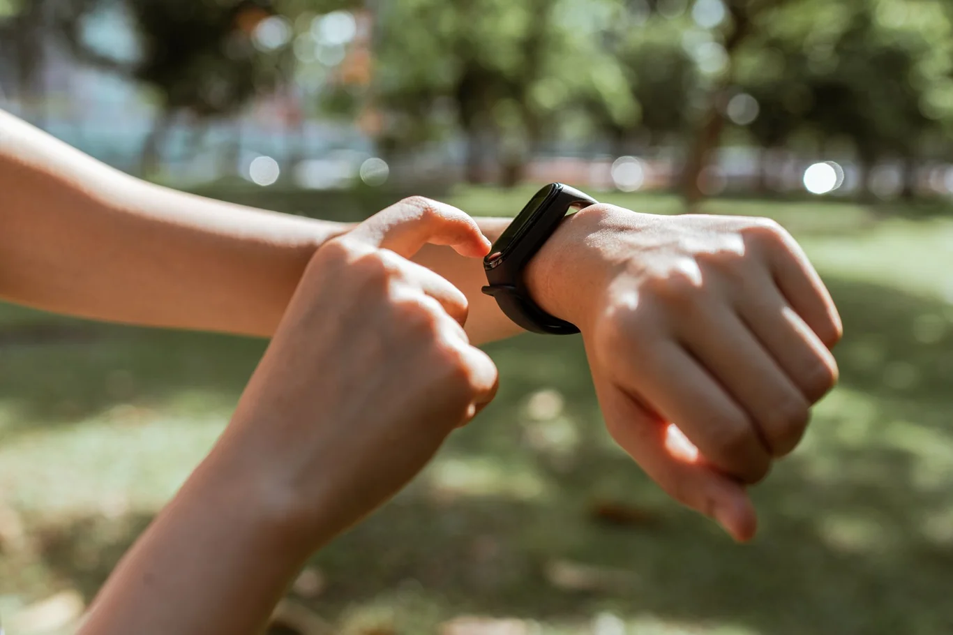 Person checking a smartwatch on a wrist outdoors in a park