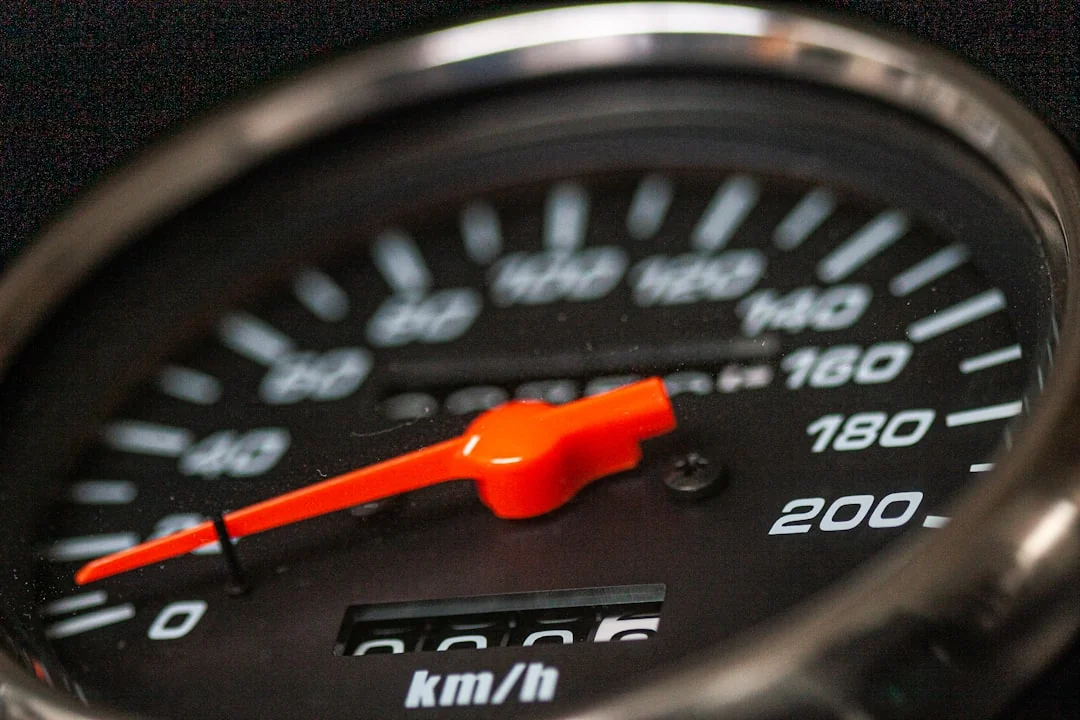 Close-up of an analog speedometer showing km/h markings with a red needle