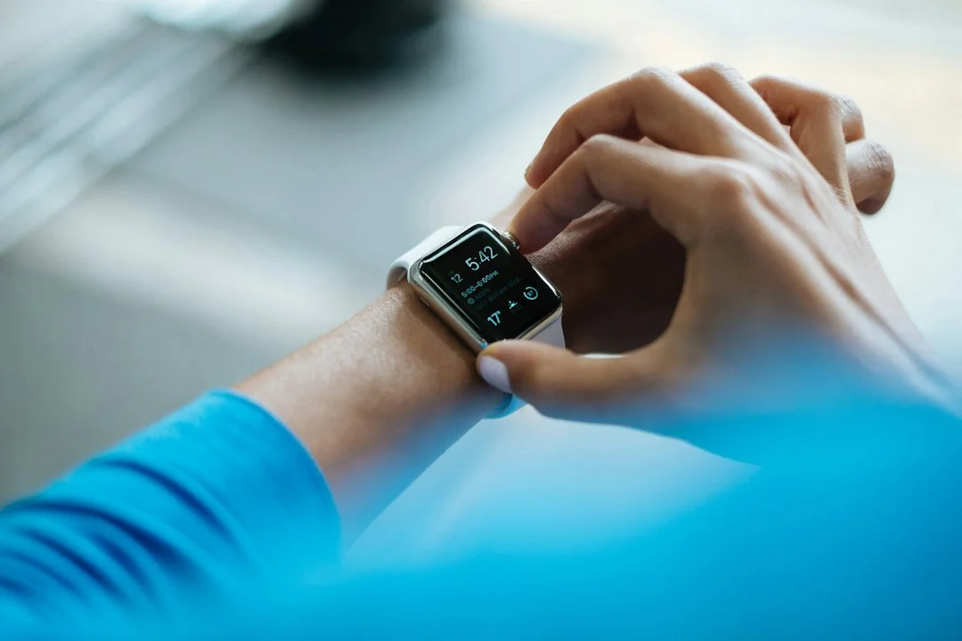 Person in blue athletic top checking a smartwatch fitness tracker on their wrist