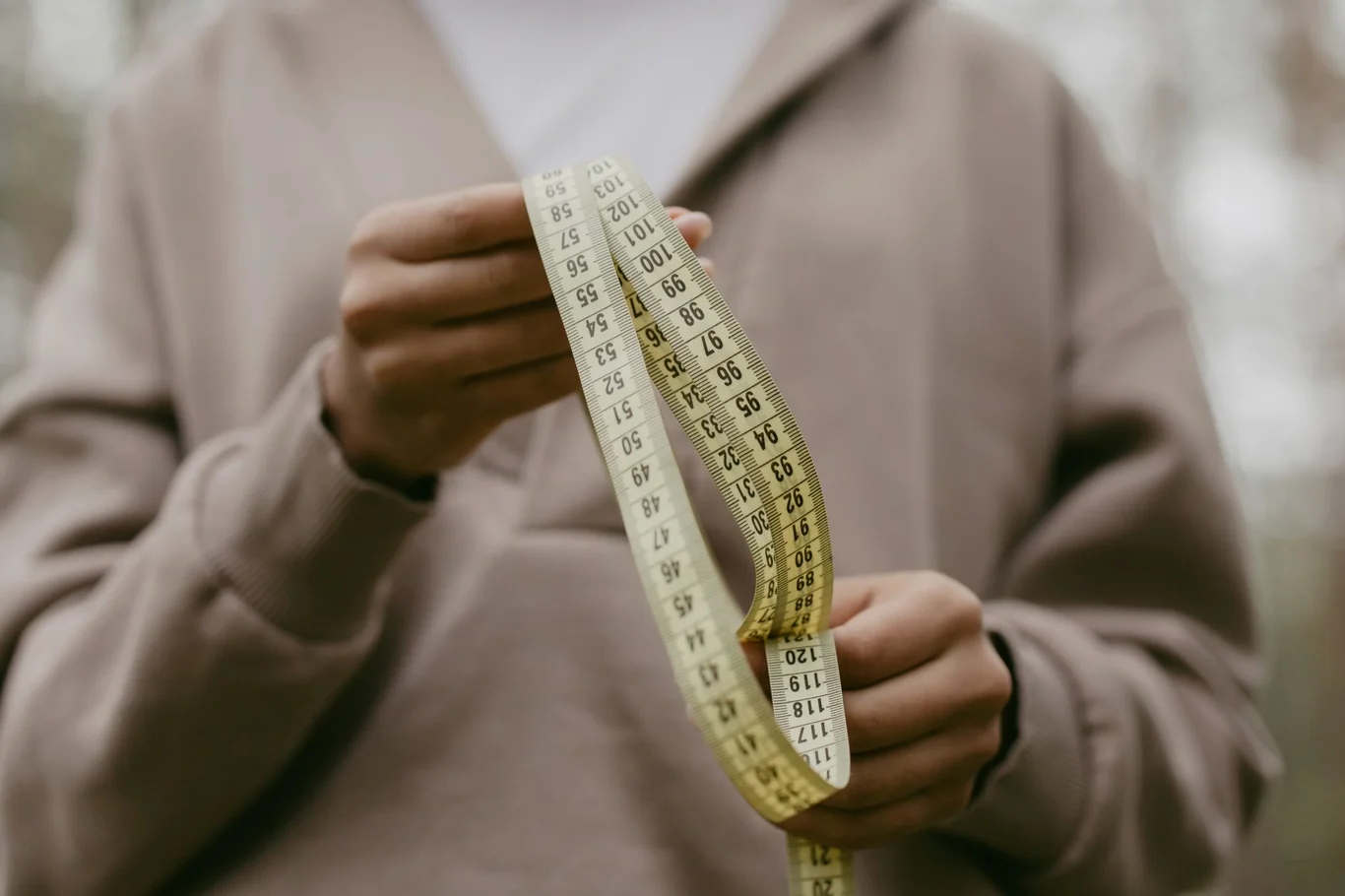 Person in a casual hoodie holding a flexible measuring tape