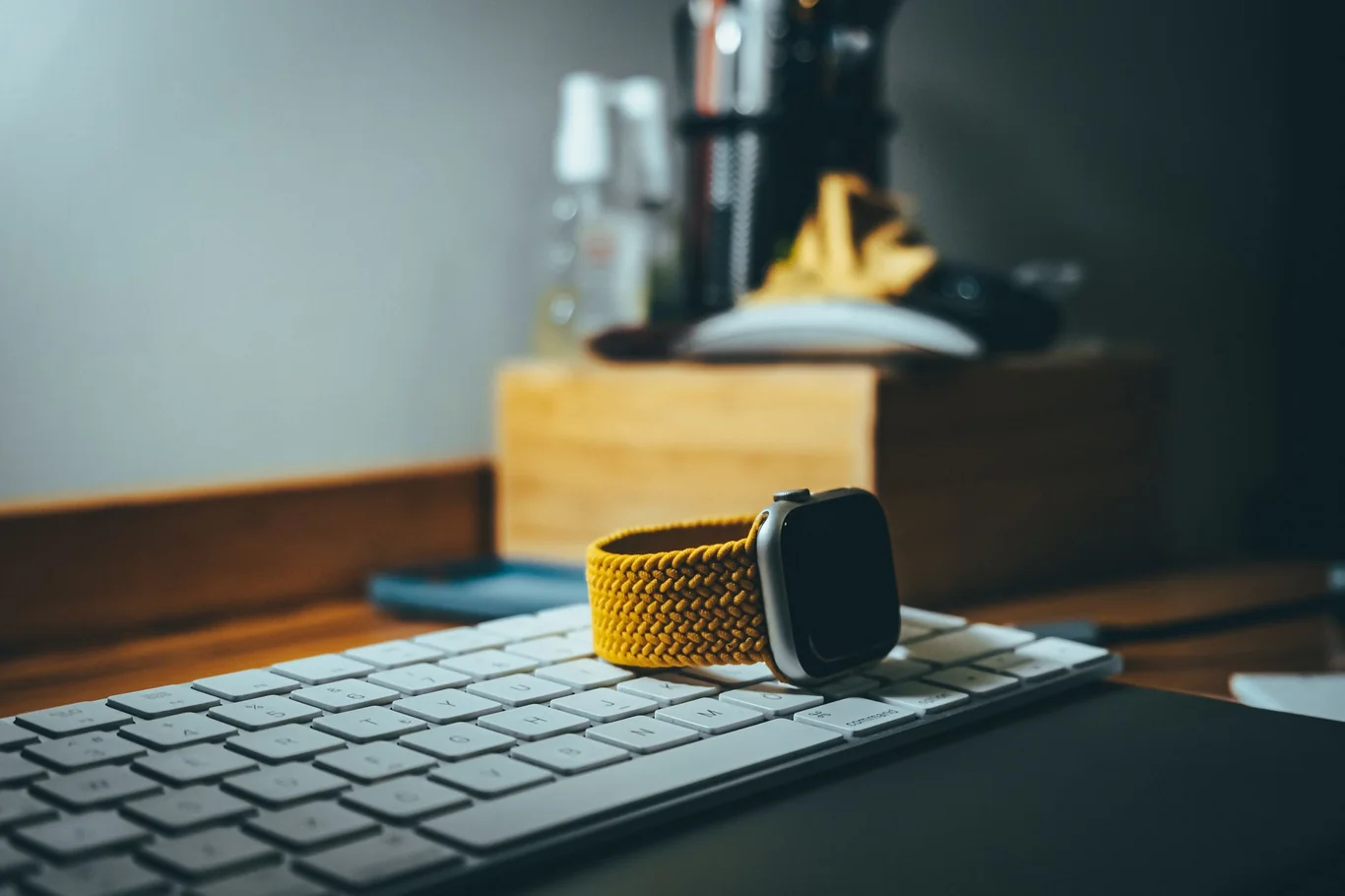 Apple Watch with yellow braided solo loop band resting on a keyboard