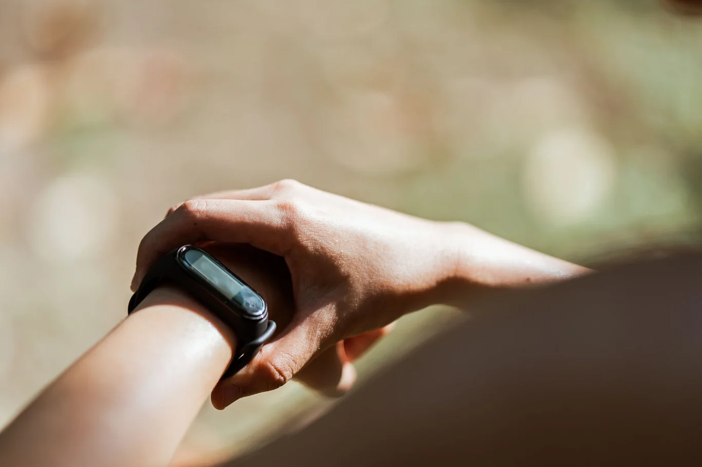 Close-up of a fitness tracker on a wrist in bright outdoor sunlight