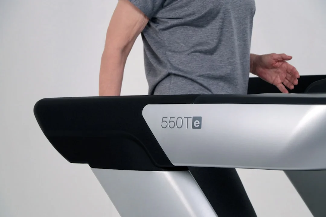 Person running a hand along the side edge of a treadmill belt to check its condition
