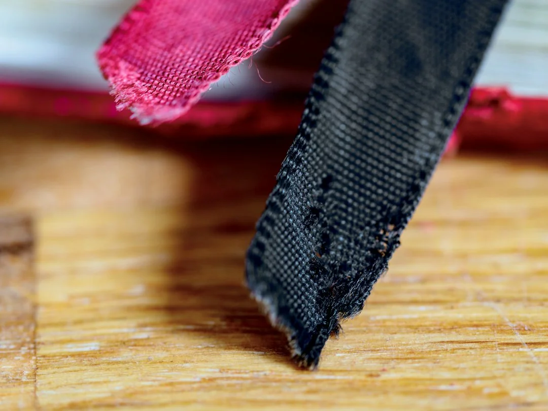 Close-up of a frayed and worn black belt edge showing visible fabric damage