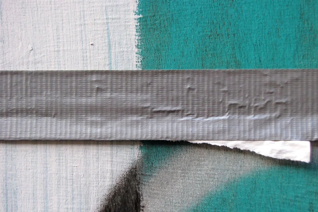 Gray repair tape applied over a cracked surface, showing a patched seam