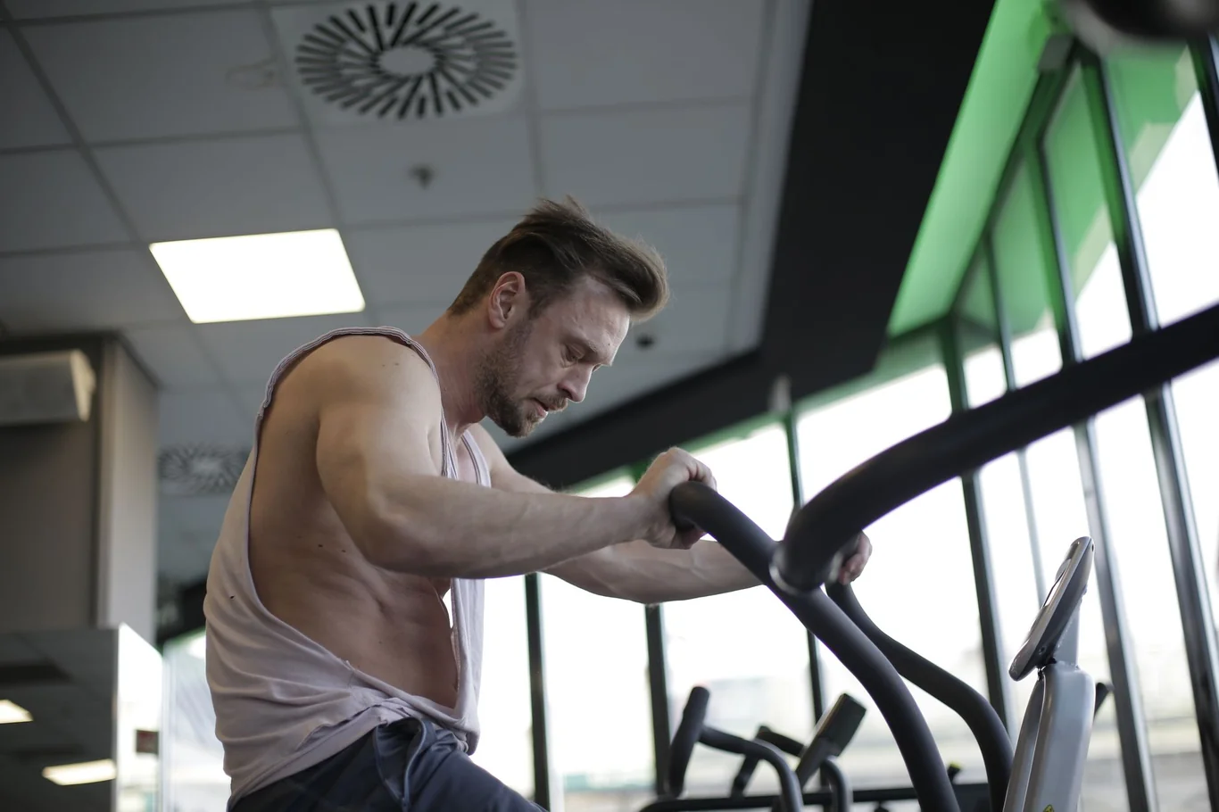 Man working out intensely on an elliptical machine at a gym