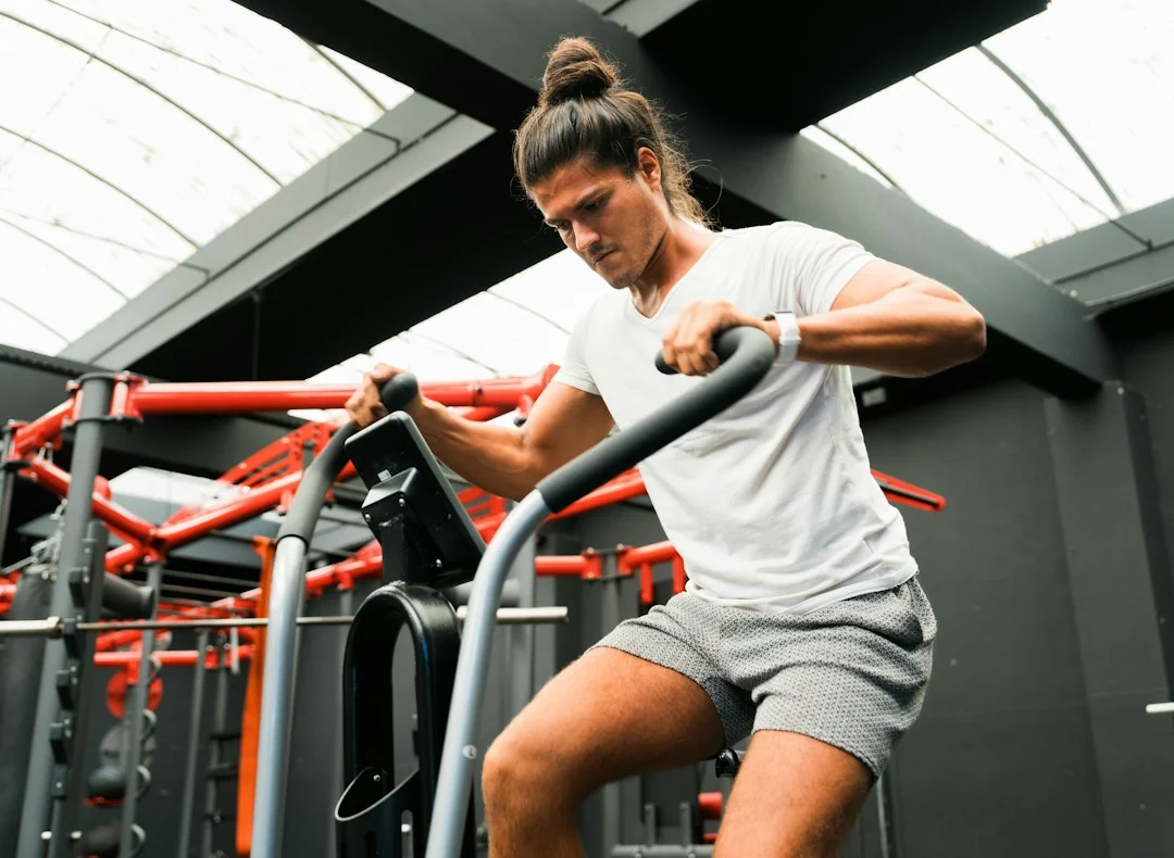 Man leaning heavily on gym machine handlebars with hunched posture during workout