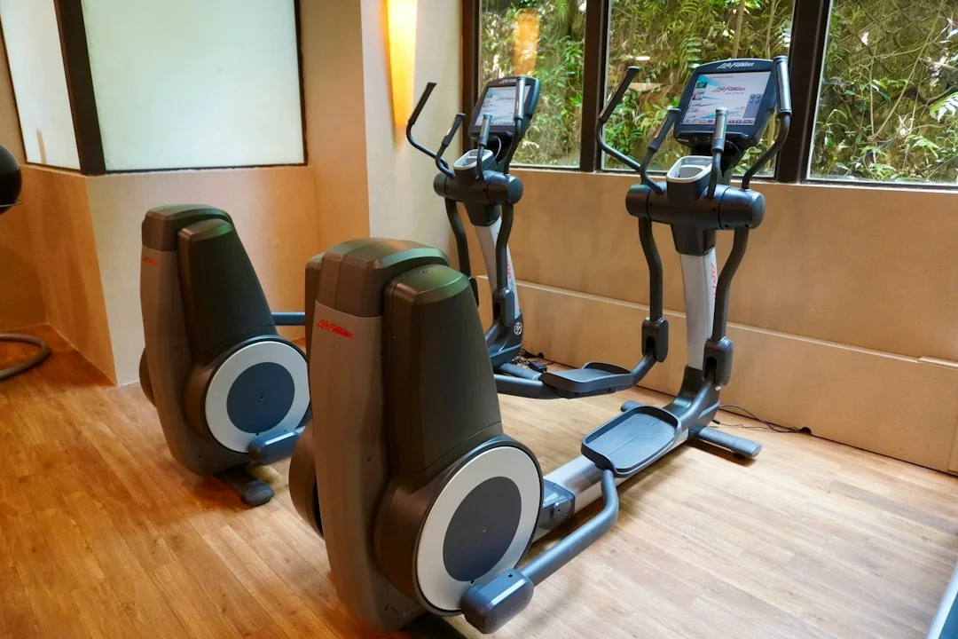 Two elliptical machines with touchscreen consoles in a bright gym near large windows