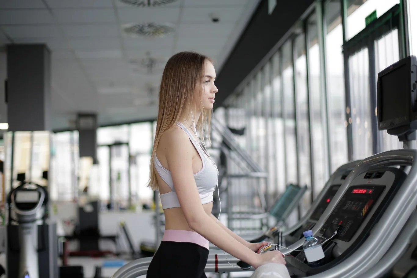 Woman in athletic wear walking on a treadmill in a bright gym